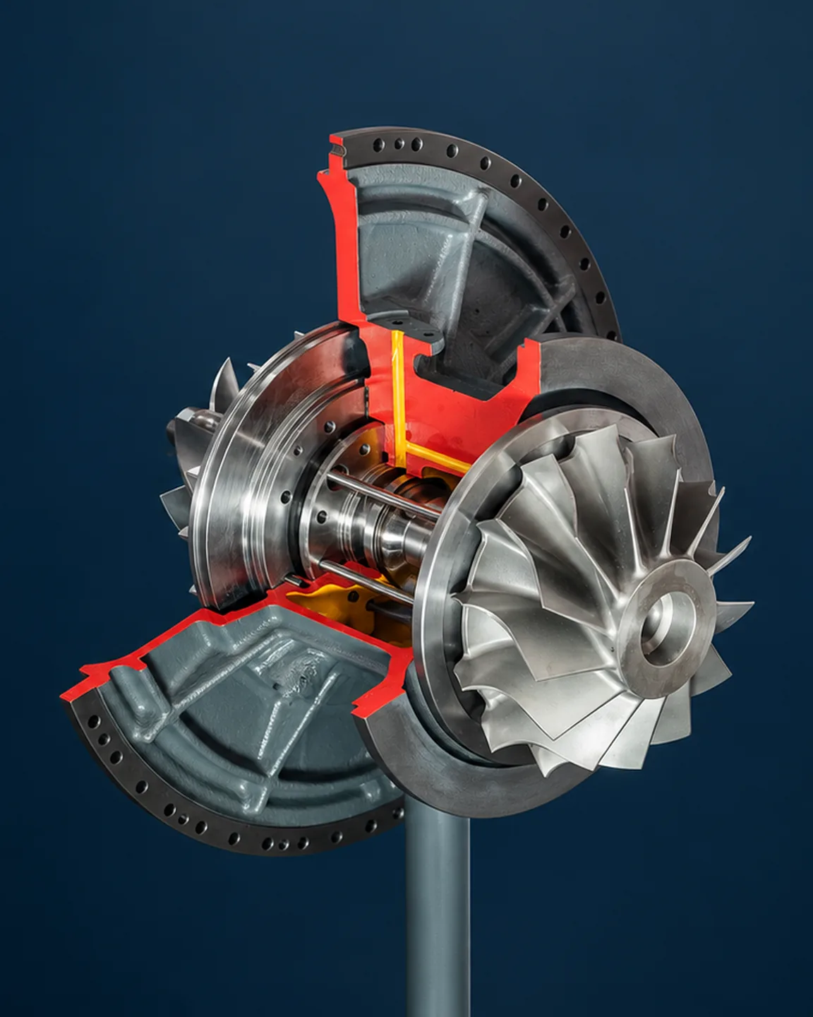 Cutaway of an STX-MAN NR34/S turbocharger on a stand, against a dark blue background